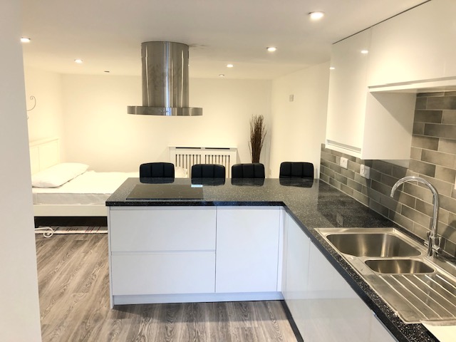 White handleless kitchen with a dark composite worktop and island hob