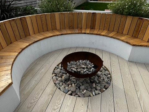 Curved oak bench and fire pit in the garden at Mordros, Trevone