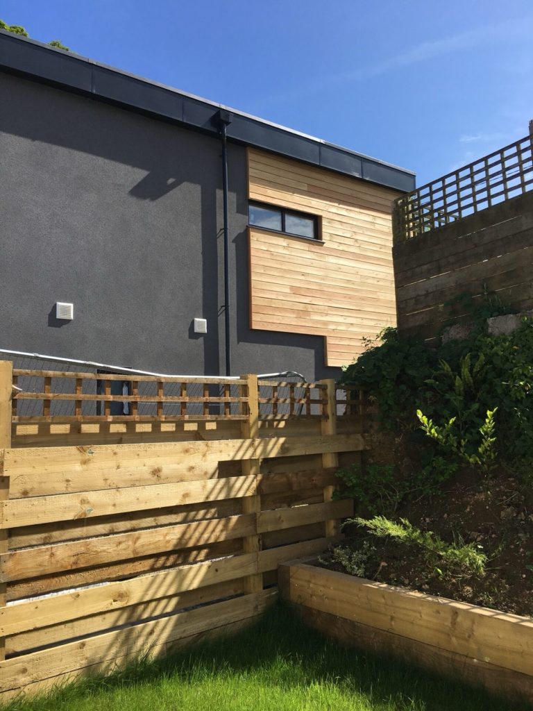 Cedar cladding on the side of the Truro new build, above a timber retaining fence